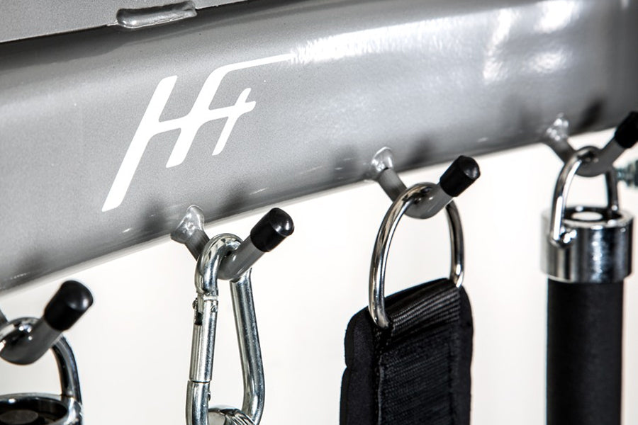 Silver BodyCraft HFT functional trainer with chrome carabiners and black handles attached, detail view of equipment logo and