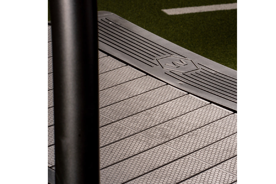 Woodway Curve LTG treadmill running surface with textured belt and black handrail, on artificial turf background