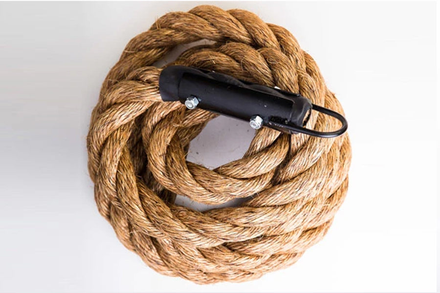Coiled natural manila climbing rope with black handles, flat lay on white background
