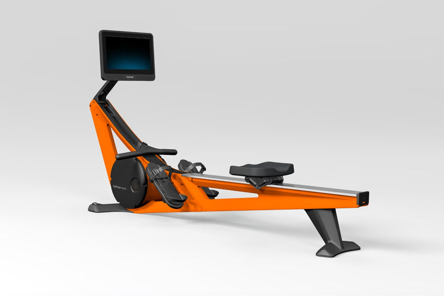Hydrow Wave rowing machine with orange and black frame, digital touchscreen monitor, and black foot platform on white backgro