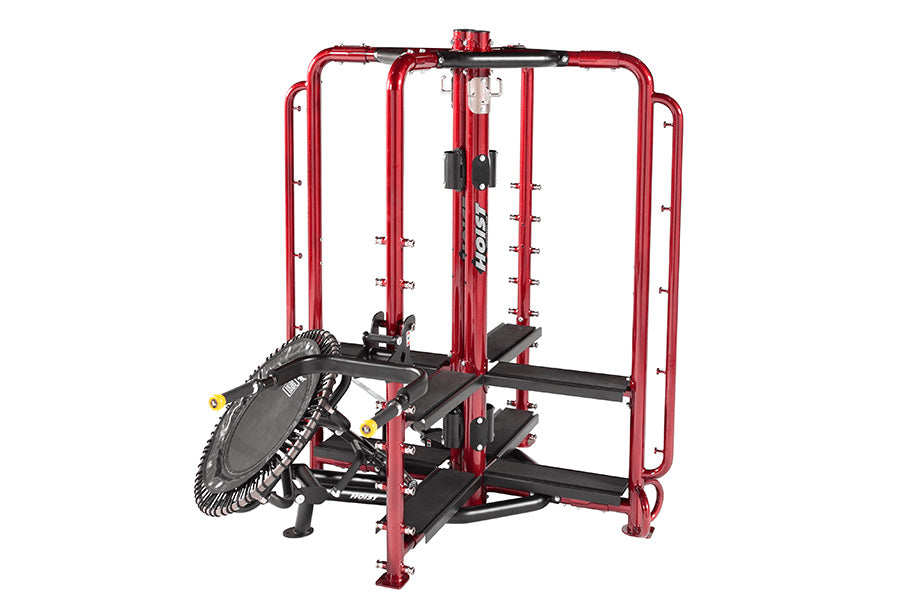 Red and black commercial multi-functional gym equipment machine with cable pulley system and leg press attachment on white ba
