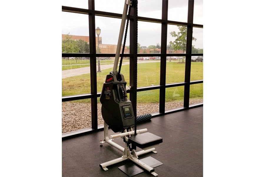 Marpo VLT Compact Rope Trainer with black resistance bag and white frame in gym setting near windows overlooking sports field
