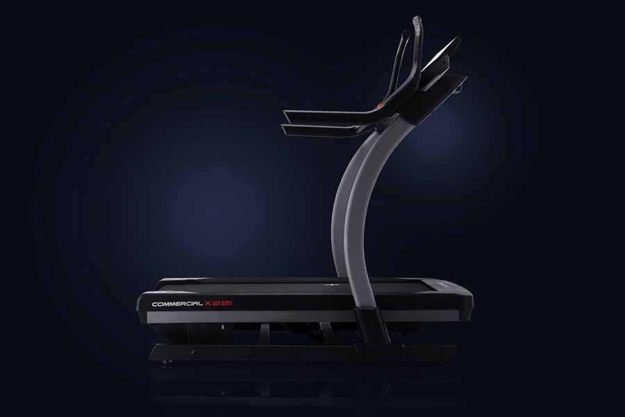 Commercial X22i treadmill with curved black base, gray curved uprights, and dual black handlebar arms on dark background