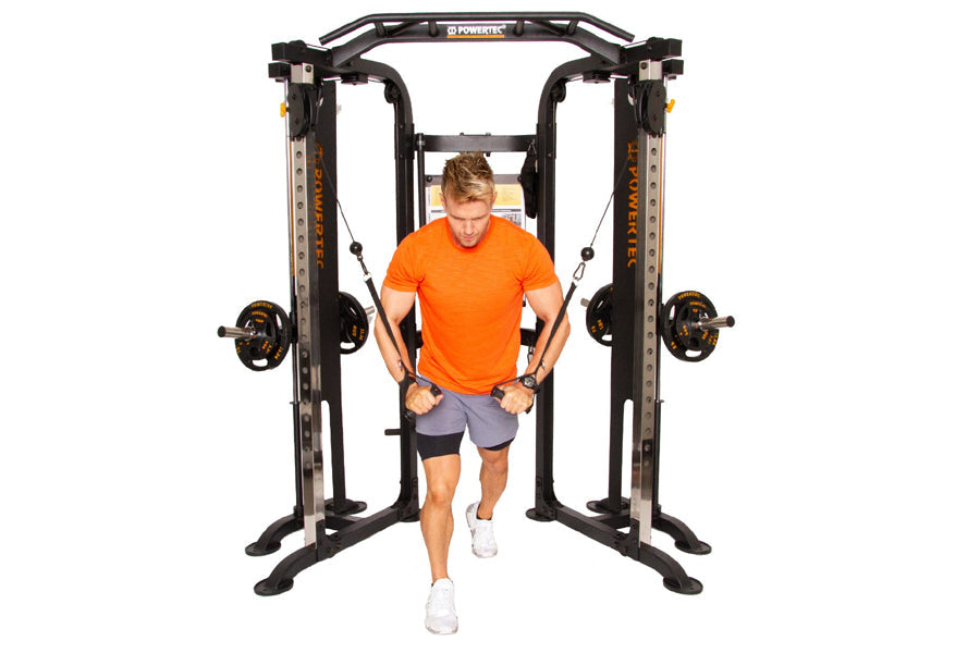 Man in orange shirt exercising on black Powertec Workbench Functional Trainer with dual weight stacks on white background
