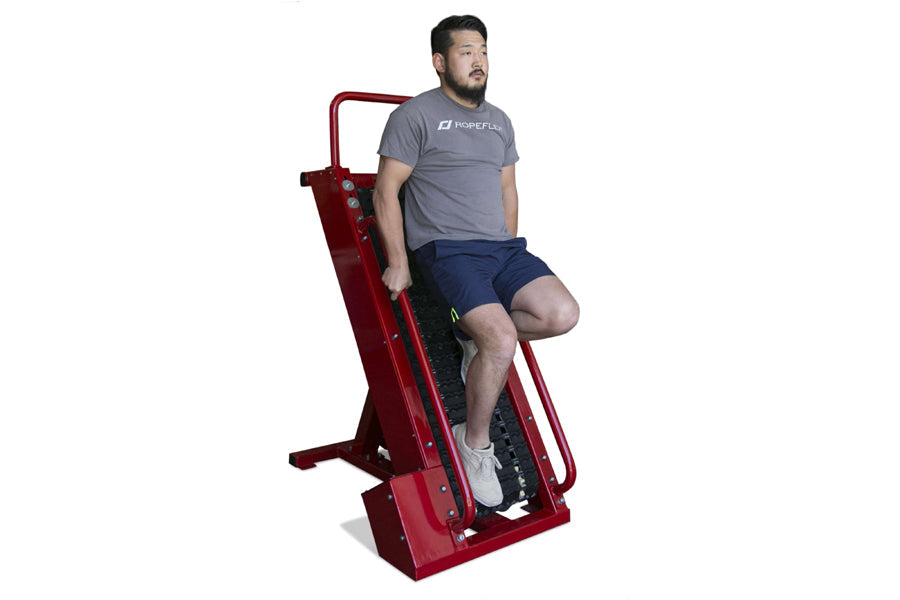 Man using red Ropeflex stair climber machine in gray t-shirt and navy shorts on white background