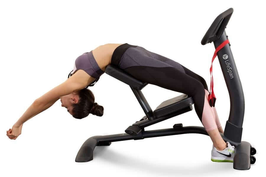 Woman demonstrating abdominal stretches on black and pink LifeSpan SP1000 Stretch Partner Pro machine with leg extension, on