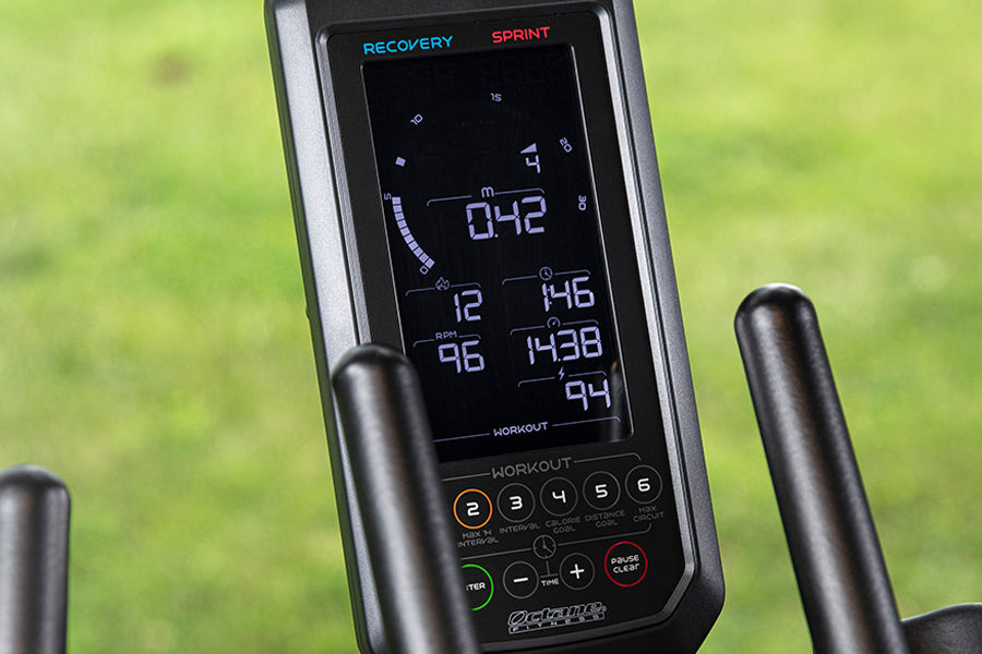 Black and gray stationary bike console displaying digital metrics including time, distance, and heart rate on screen, with Re