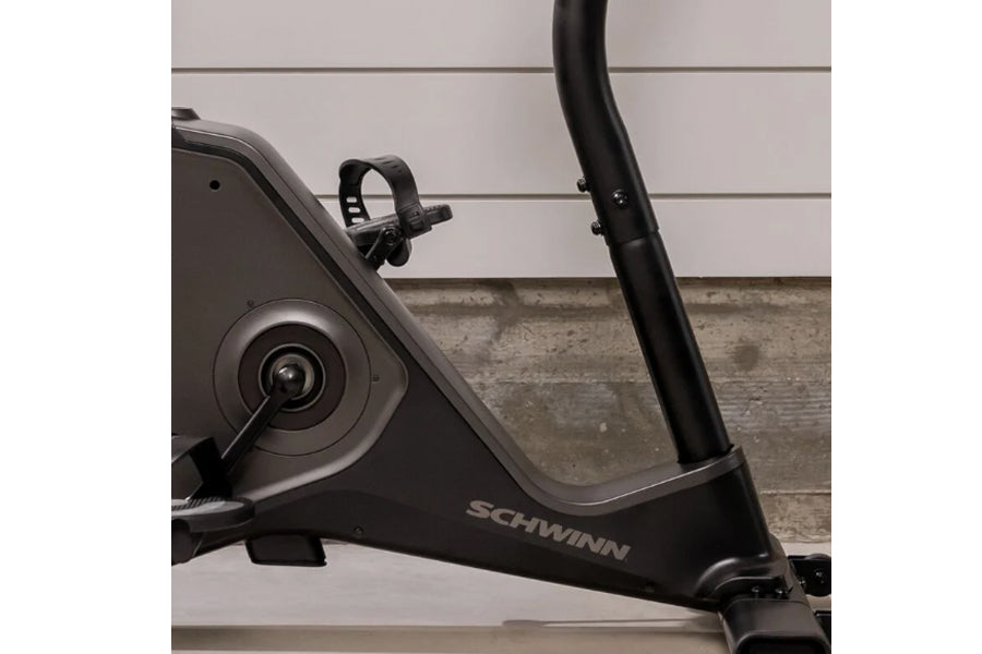 Schwinn 190 upright exercise bike with black frame, flywheel, and vertical handlebars against brick wall