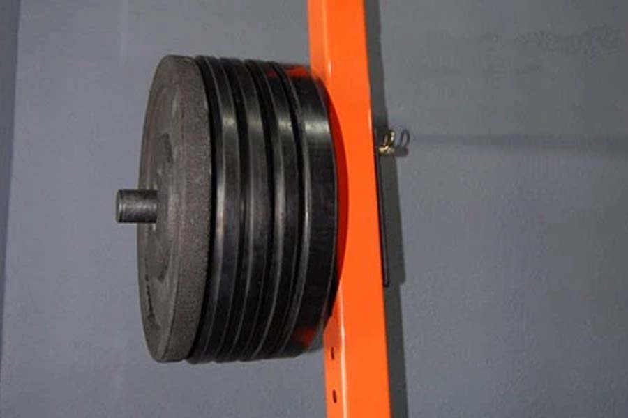 Warrior single weight plate storage rack attachment with black metal plates mounted on bright orange vertical frame