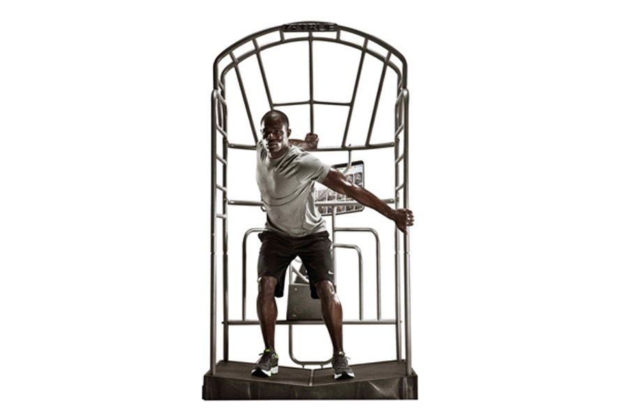 Man exercising on TRUE Stretch training machine with metal frame and black platform, demonstrating stretching position