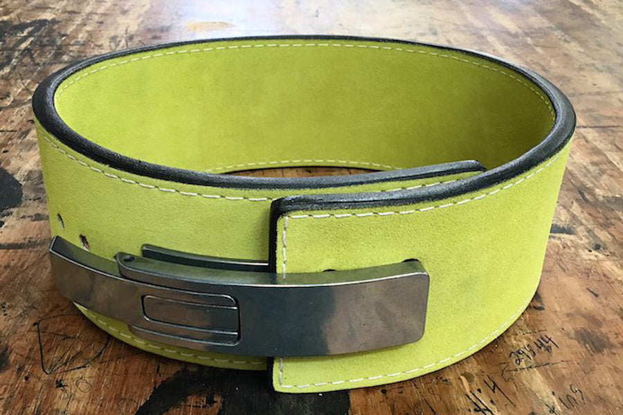 Lime green leather weightlifting belt with black metal lever buckle and black trim, flat lay on wood background