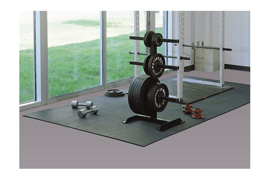 Warrior rubber gym floor mat in dark gray, shown in home gym setting with weight plates, barbell, dumbbells and rack