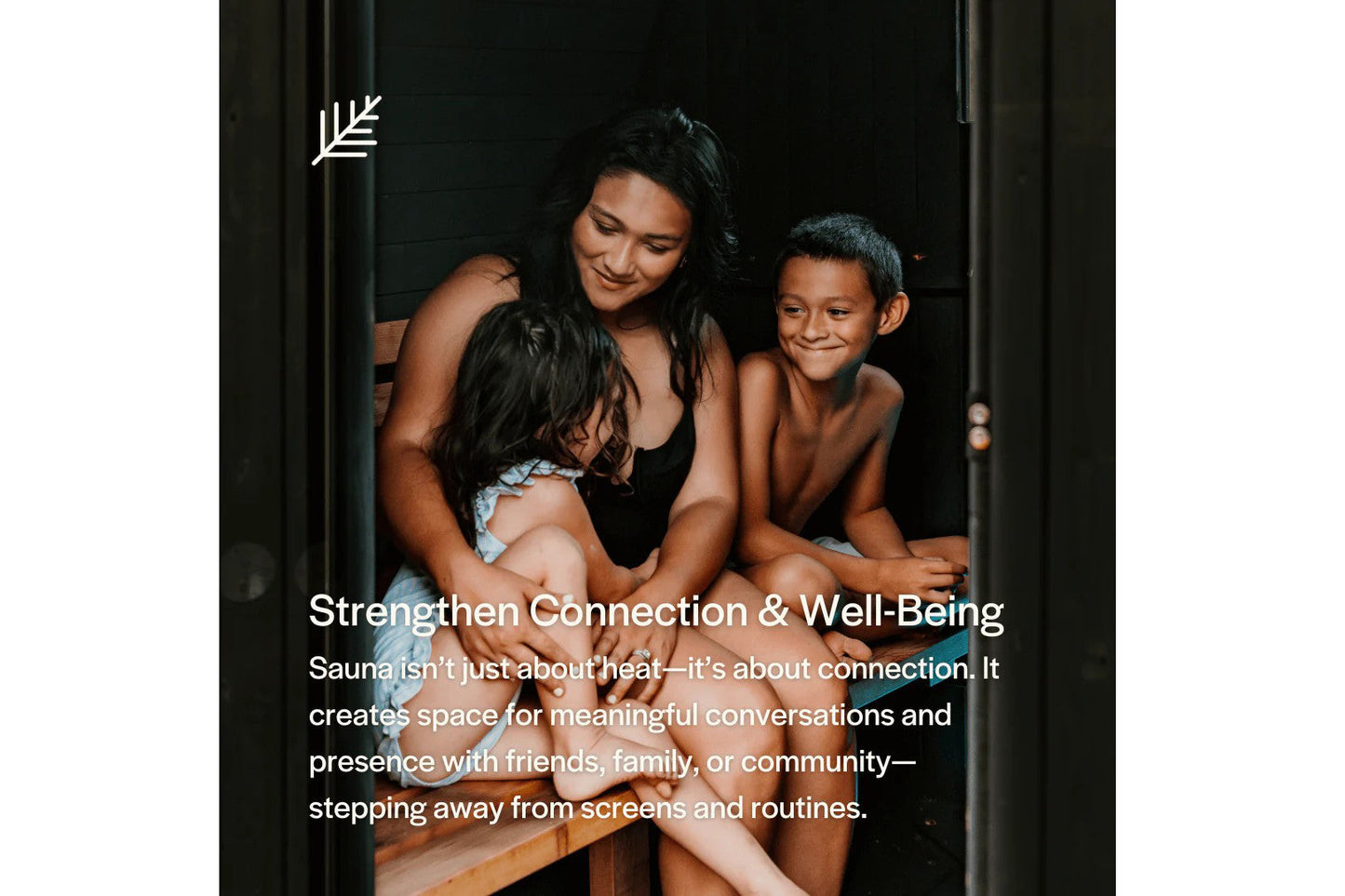 Woman and two children sitting together inside wooden sauna with black interior walls