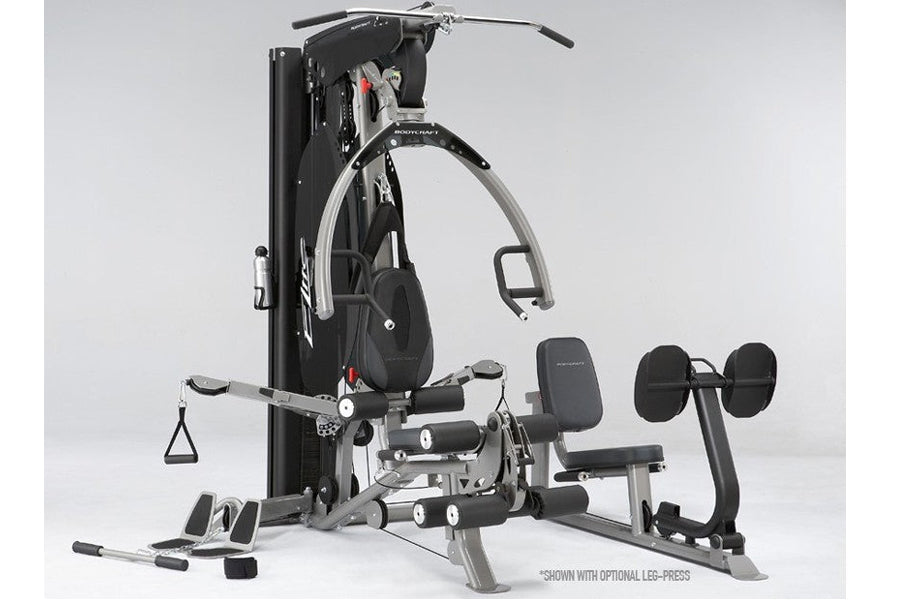 BodyCraft Elite home gym system with black frame, leg press attachment, adjustable seat, cable machine, and dumbbell weights