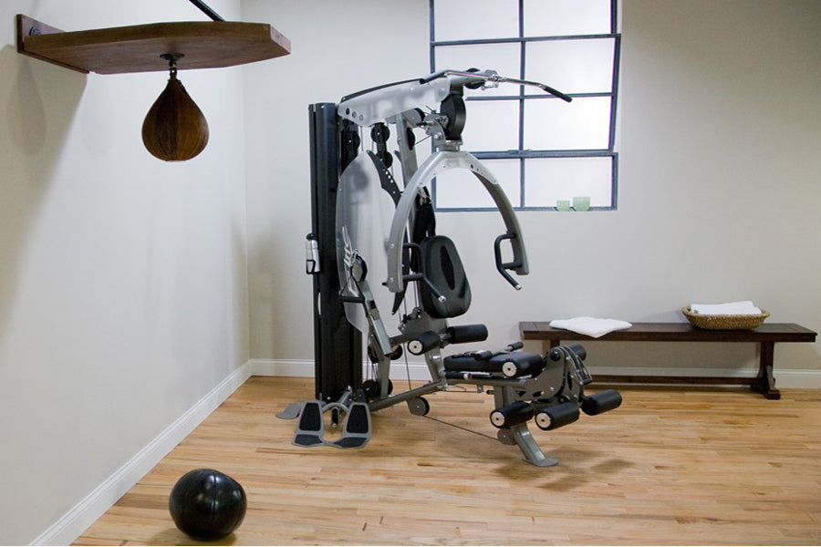 BodyCraft Elite home gym with white and black strength machine, attached weights, and leg extension, displayed in studio sett