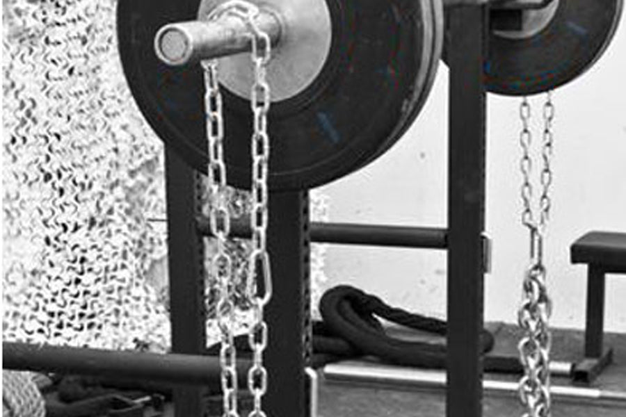 Warrior Chain Attachment Kit with metal chains and silver carabiners attached to black weight plate rack in gym setting