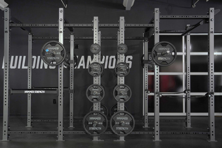 Hammer Strength HD Athletic NX Power Half Combo Rack with white steel frame and black weight plates, front view on dark backg