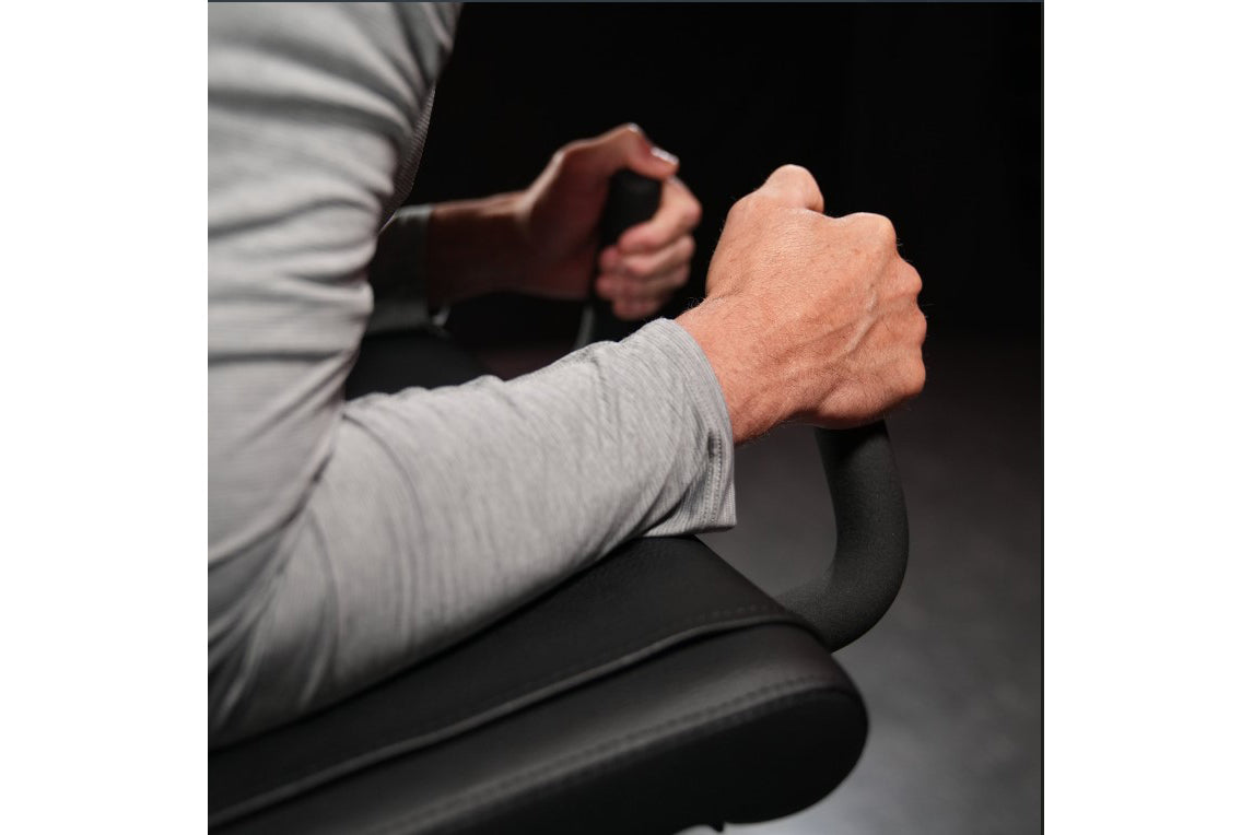 Man using black Hammer Strength plate-loaded iso-lateral kneeling leg curl machine, wearing light gray long-sleeve shirt