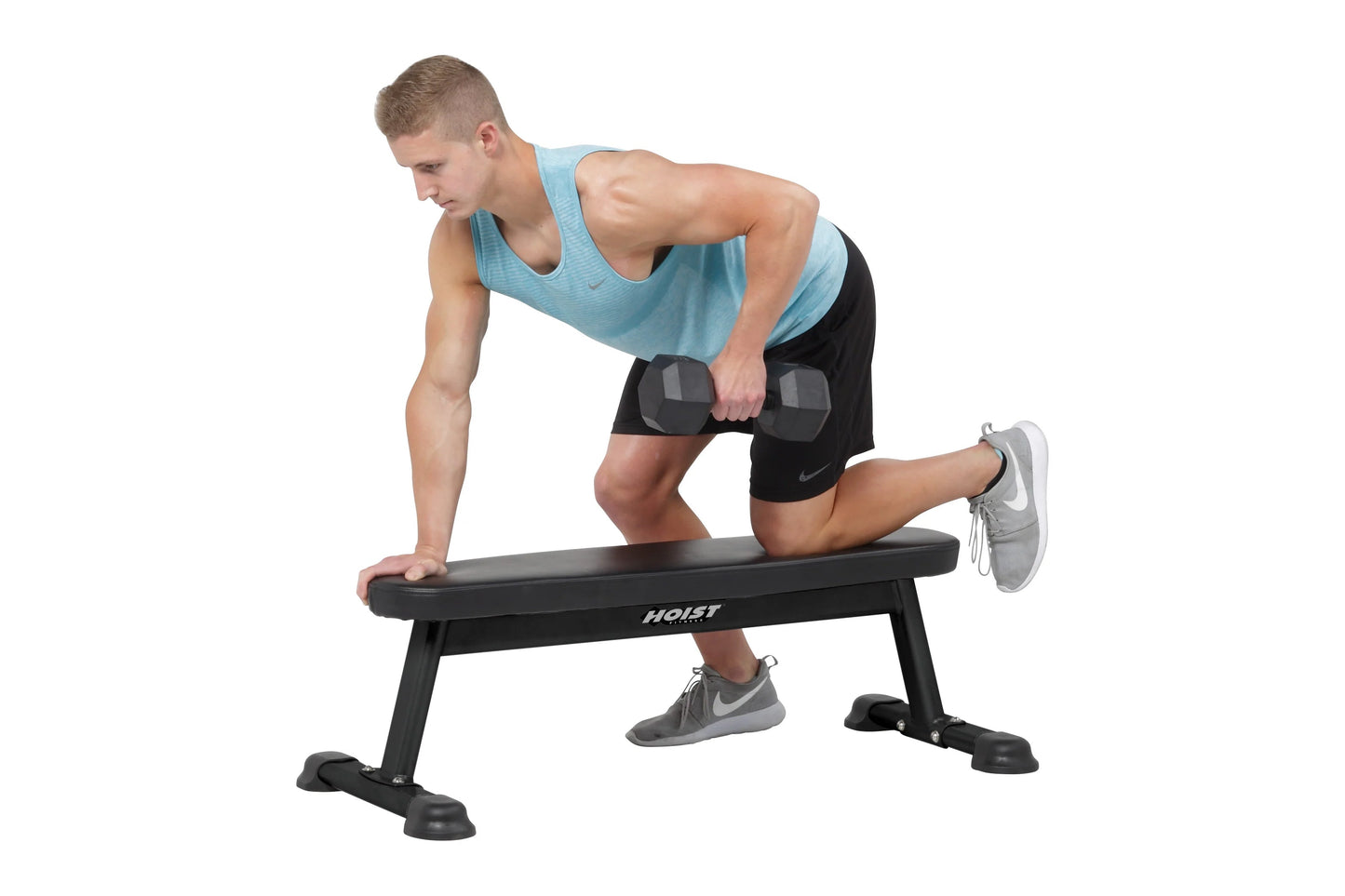 Man performing dumbbell exercise on black Hoist flat utility bench, wearing light blue tank top and black shorts