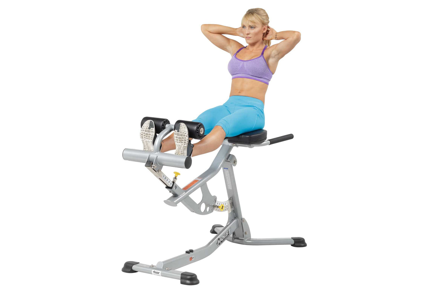 Woman using gray Hoist ab and back Roman hyper bench, wearing purple sports bra and blue leggings on white background