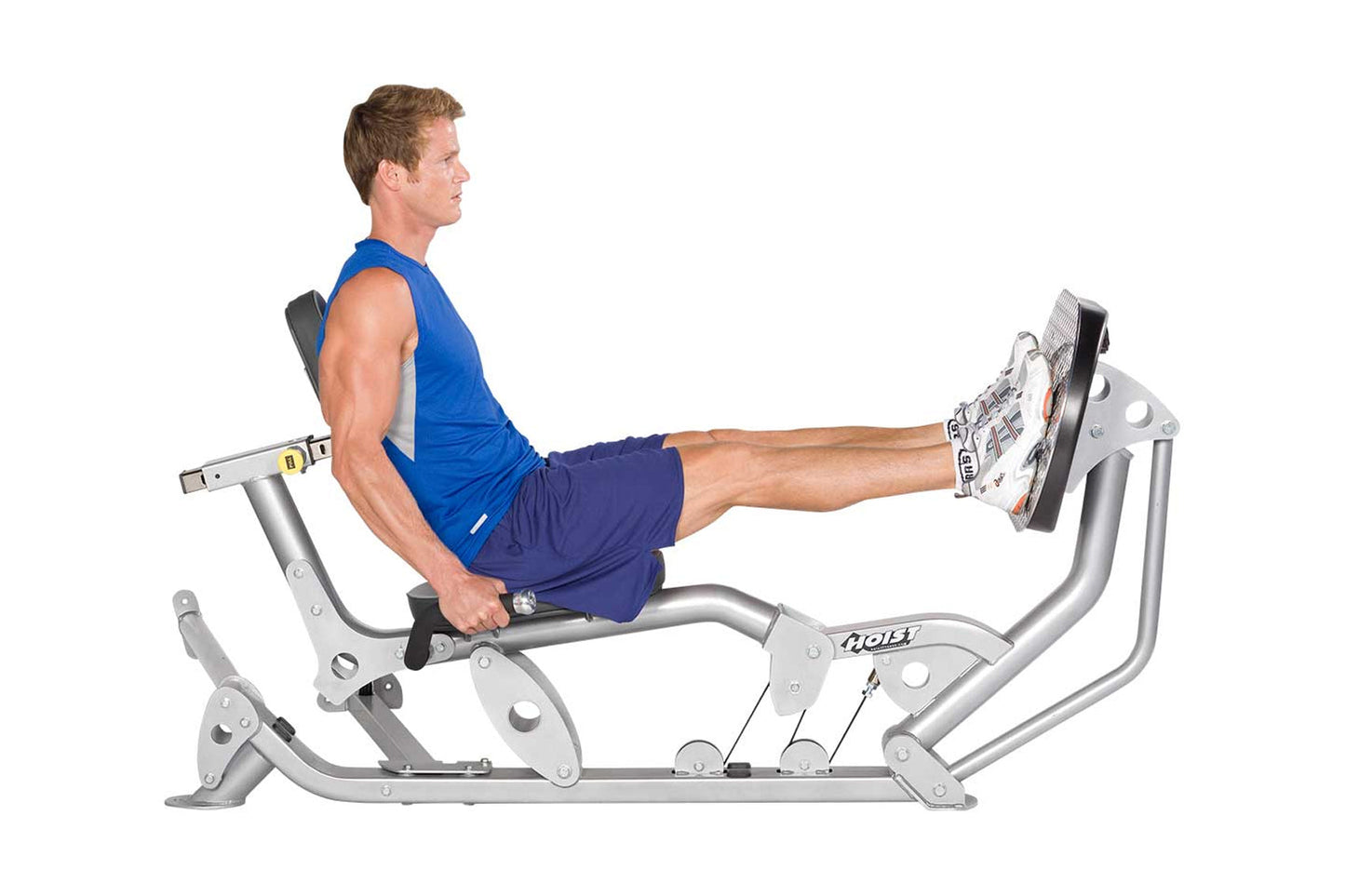 Man in blue tank top and navy shorts using silver Hoist leg press machine with extended leg position on white background