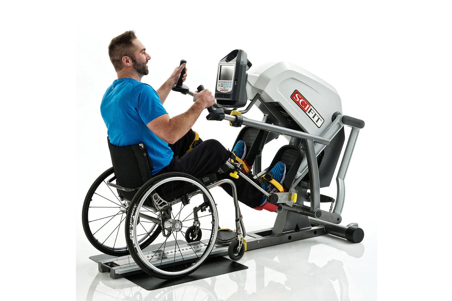 Man in blue shirt using white and black recumbent stepper exercise machine with digital display, seated in wheelchair on whit