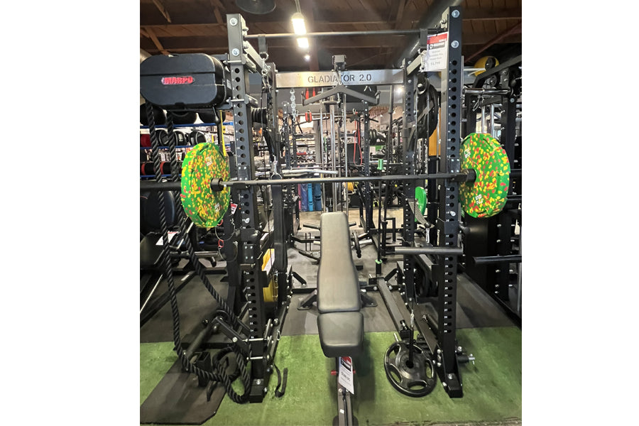 Warrior Gladiator 2.0 black power rack with neon green weight plates, bench, and lat pulldown attachment in gym setting