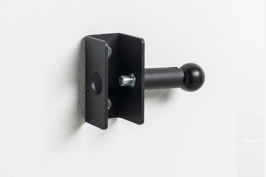 Black wall-mounted fold-up squat rack attachment with adjustable J-cup and lever arm, mounted on white wall