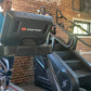 Person wearing blue tank top and patterned leggings using Star Trac treadmill in brick gym, StairMaster equipment visible nea
