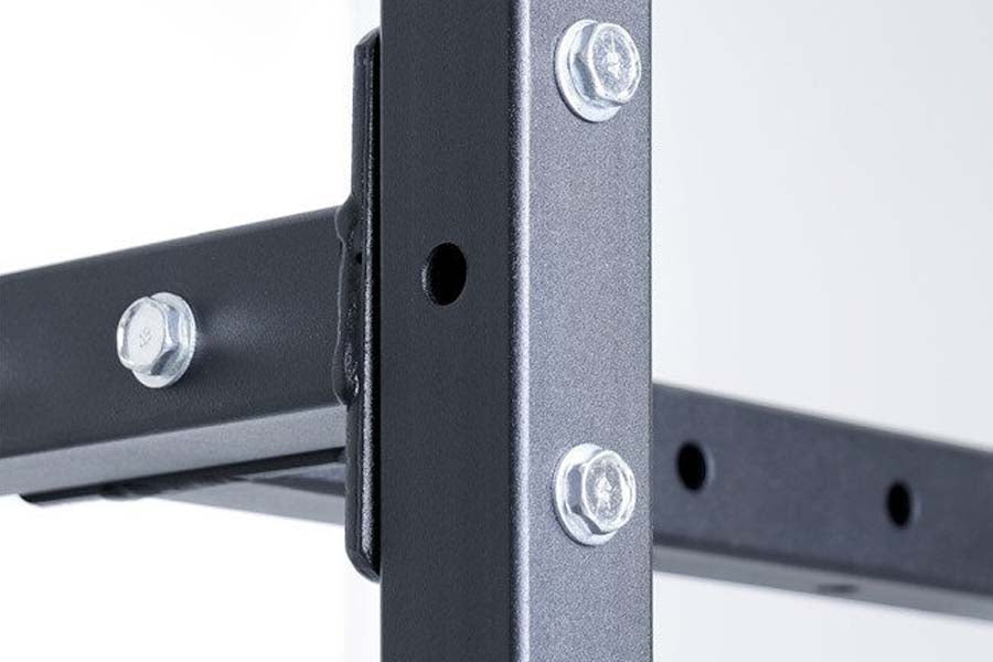 Black metal storage rack frame with adjustable horizontal bars and chrome bolts, detail view of corner joint on white backgro