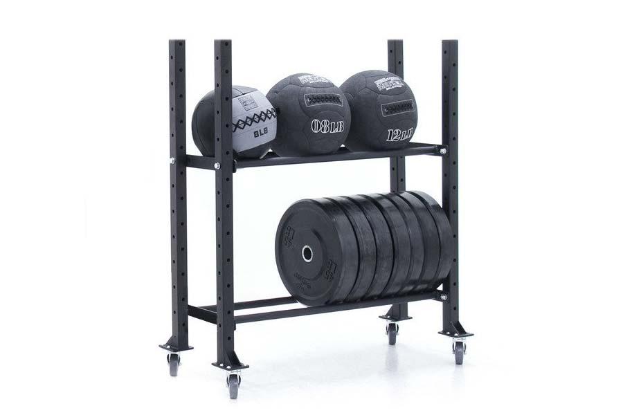 Black two-tier storage rack with four caster wheels holding medicine balls on upper shelf and weight plates on lower shelf