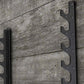 Pair of black metal barbell racks with six tiered hooks mounted on concrete wall
