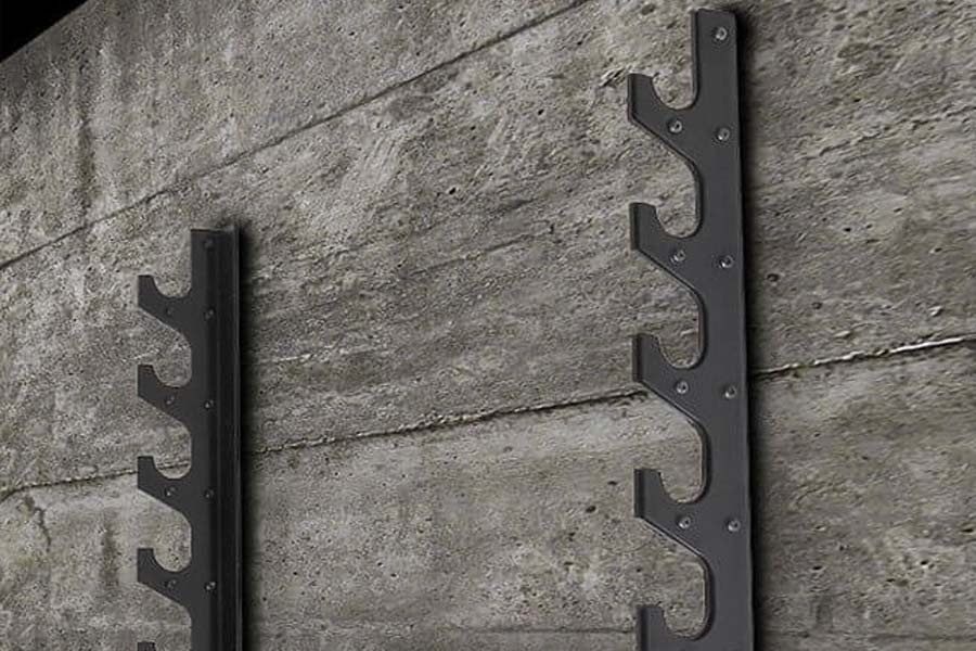 Pair of black metal barbell racks with six tiered hooks mounted on concrete wall