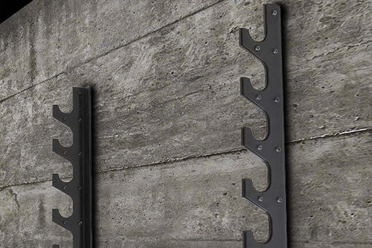 Pair of black metal barbell racks with six tiered hooks mounted on concrete wall