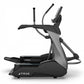 Black and gray commercial elliptical machine with dual handles, foot pedals, and digital display on white background