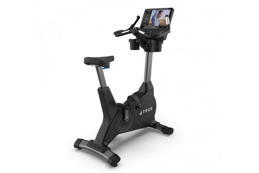 TRUE 900 upright exercise bike with black frame, gray column, padded seat, and digital display console on white background