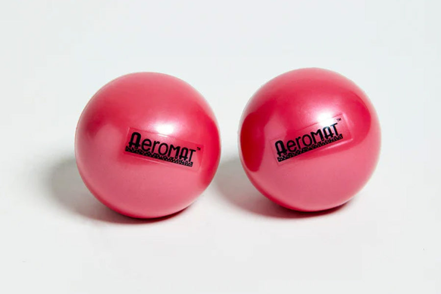 Pair of bright pink Aeromat mini weight balls with black logo text, shown on white background