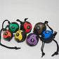 Seven colorful medicine balls with attached black ropes arranged on white background, featuring numbered weights in green, re
