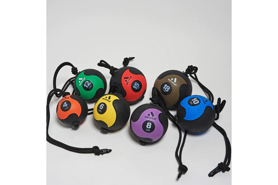 Seven colorful medicine balls with attached black ropes arranged on white background, featuring numbered weights in green, re