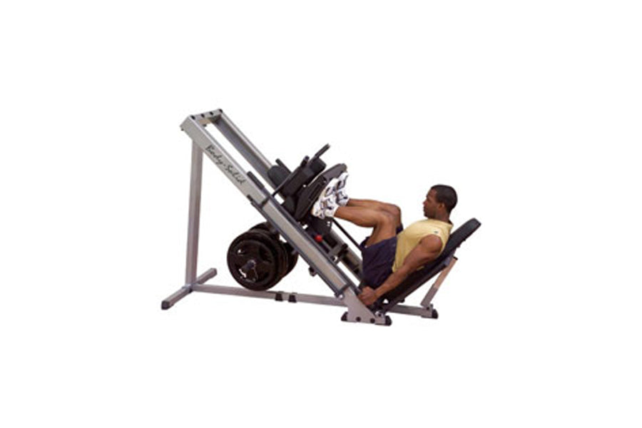 Body-Solid leg press and hack squat machine with gray frame and black weight plates, demonstrated by man in yellow tank top o