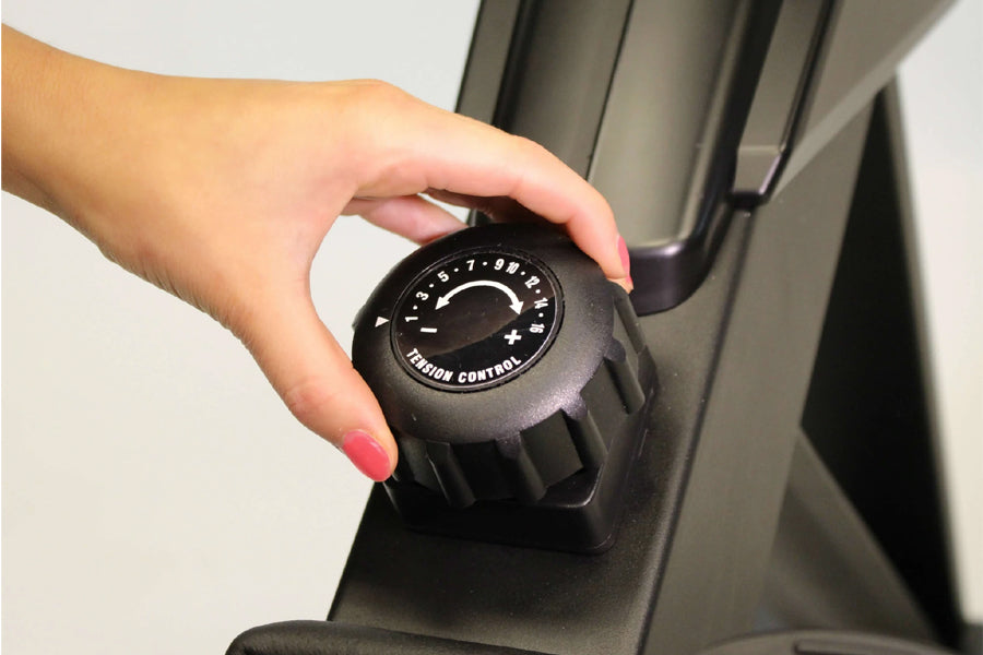 Hand adjusting black tension control dial on BodyCraft VR400 Pro rowing machine