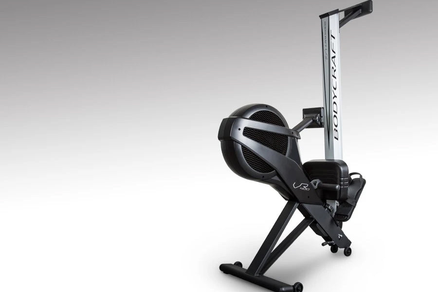 Black and silver BodyCraft VR400 Pro rowing machine with large fan wheel and vertical frame on gray background