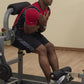 Man wearing red and black athletic shirt using gray and black stationary ab and back exercise machine with foot pedal