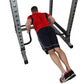 Man performing dip exercise on gray metal bar attachment with red shirt and navy shorts, viewed from above on white backgroun