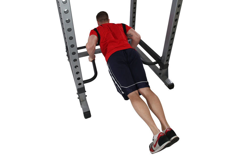 Man performing dip exercise on gray metal bar attachment with red shirt and navy shorts, viewed from above on white backgroun