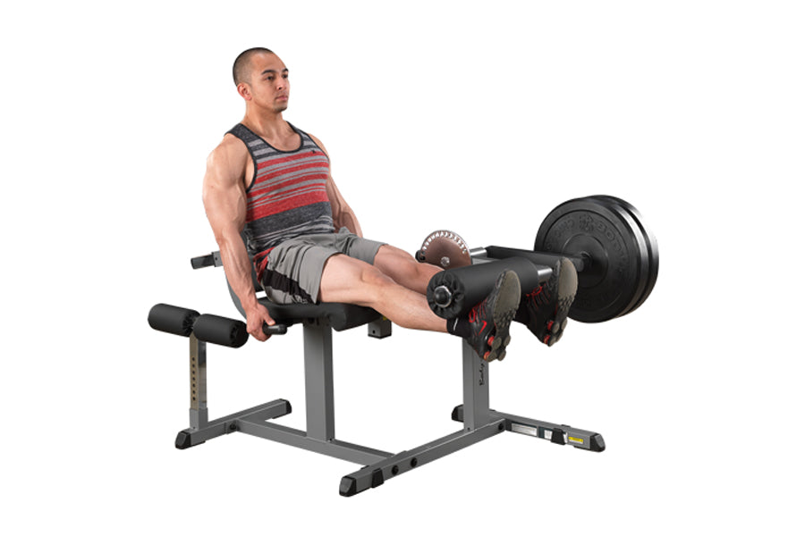 Man using gray and black leg extension machine with barbell weight, worn by model on white background