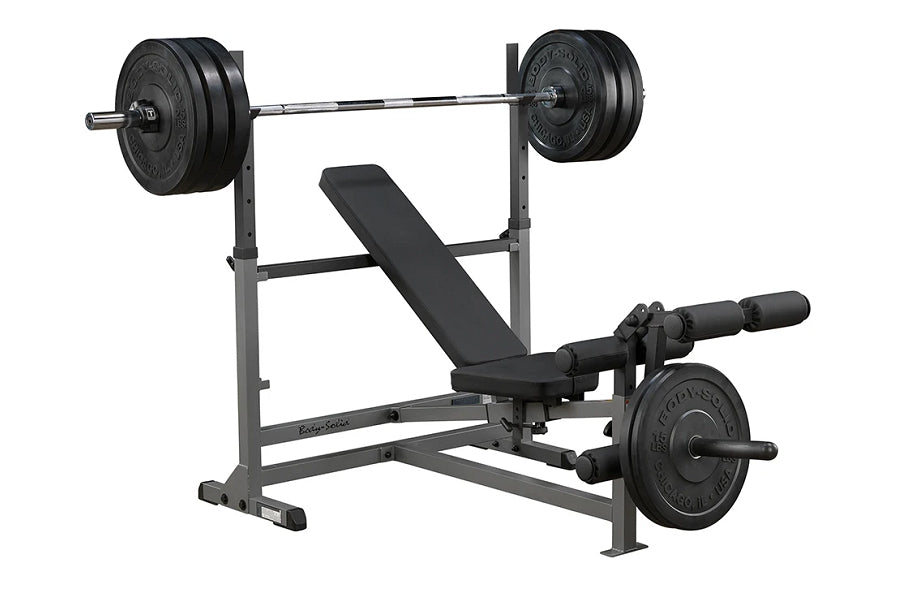 Body-Solid PowerCenter Combo Bench with black weight plates on barbell and leg attachment, gray steel frame on white backgrou