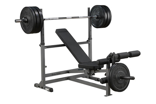 Body-Solid PowerCenter Combo Bench with black weight plates on barbell and leg attachment, gray steel frame on white backgrou