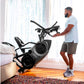 Man in light blue t-shirt and gray shorts using black Bowflex Max Trainer M9 elliptical machine in bright home gym with windo