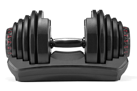 Bowflex SelectTech adjustable dumbbell with black weight plates and red numbered dial, resting on gray base, front view